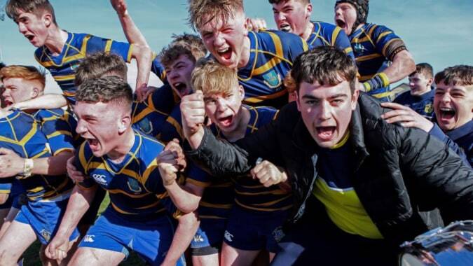 Eine Gruppe von Rugby-Spielern in Uniform auf dem Außengelände des Marist College versammelt.