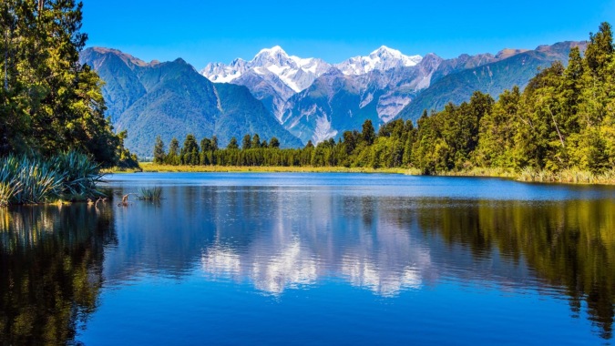 Der ruhige See mit grünen Wäldern und schneebedeckten Bergen spiegelt sich auf dem Campus des Marist College.