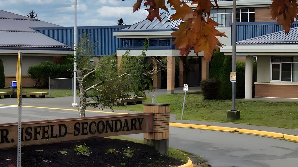Der Campus der Mark R. Isfeld Secondary School mit einem Schulwegschild und von Bäumen sowie bunten Gebäuden umgeben.