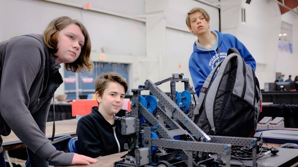 Zwei Schüler und ein Erwachsener arbeiten gemeinsam an einem Robotikprojekt in der Werkstatt der Mark R. Isfeld Secondary School.