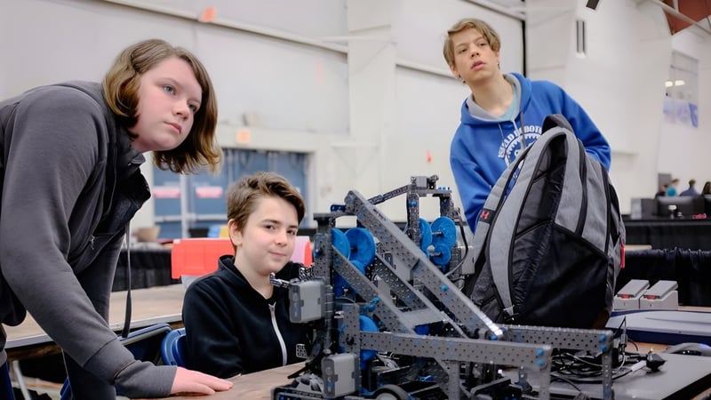 Zwei Schüler und ein Erwachsener arbeiten gemeinsam an einem Robotikprojekt in der Werkstatt der Mark R. Isfeld Secondary School.