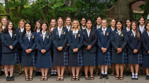 Eine Gruppe junger Schülerinnen der Marlborough Girls steht gemeinsam in einer bewaldeten Außenanlage.