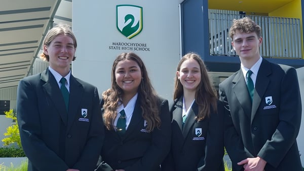 Vier Schülerinnen und Schüler stehen vor dem Gebäude der Maroochydore State High School in Schuluniformen.