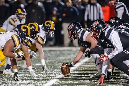 Schüler der Marquette High School stehen in Teamuniform bereit für den nächsten Spielzug im Footballspiel.