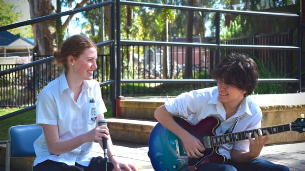 Zwei Schülerinnen und Schüler der Marryatville High School führen ein Gespräch, während der Schüler Gitarre spielt.