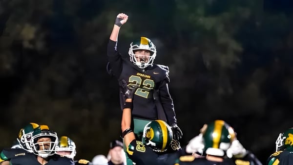 Ein Footballspieler der Martin Luther High School mit der Nummer 22 feiert auf dem Spielfeld mit seinen teammates.