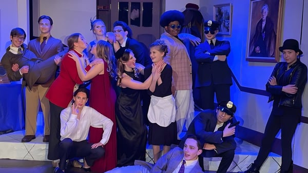 Eine Gruppe von Menschen in formeller und legerer Kleidung in einem Innenraum auf dem Campus der Martin Luther High School vor Kunstwerken und Porträts.