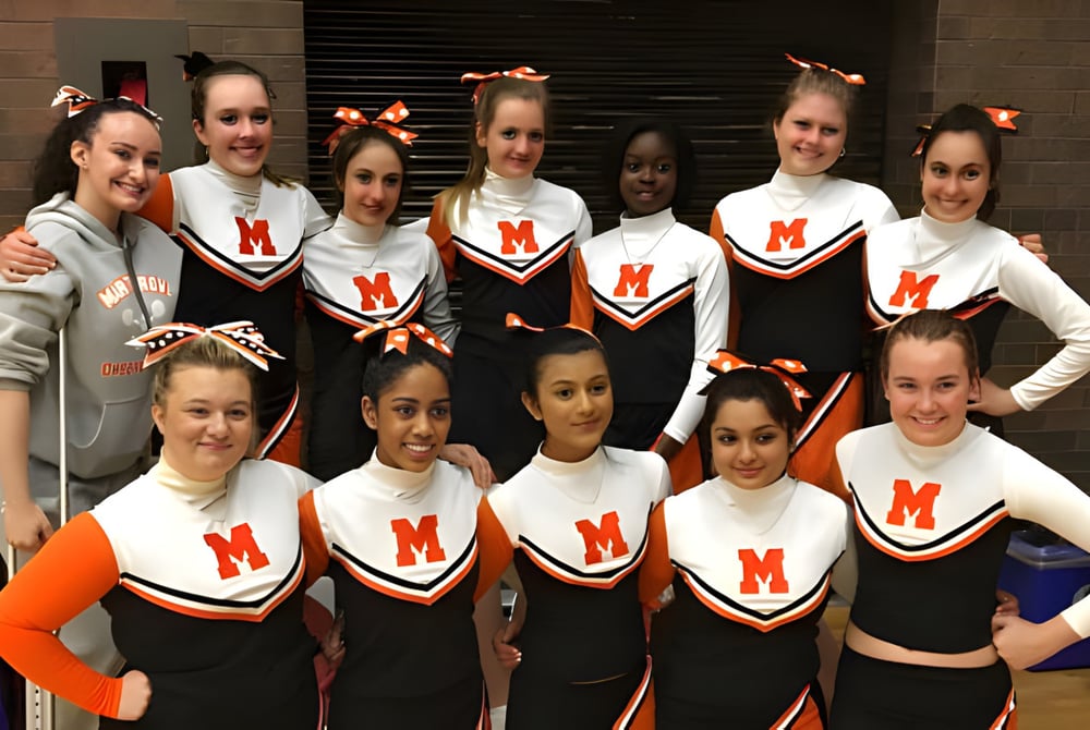 Eine Gruppe junger Cheerleaderinnen in einheitlichen Uniformen posiert vor einer Backsteinwand auf dem Campus der Martingrove Collegiate Institute.