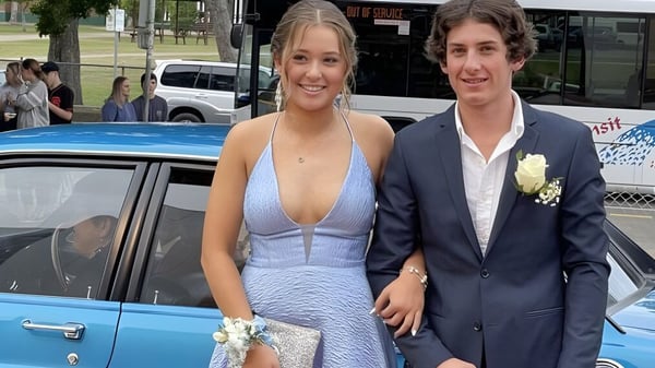 Ein junges Paar steht vor einem blauen Auto vor der Maryborough State High School.