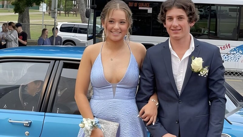 Ein junges Paar steht vor einem blauen Auto vor der Maryborough State High School.