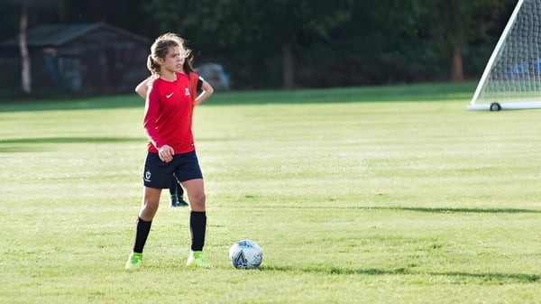 Eine junge Fußballspielerin der Marymount International School steht auf dem Spielfeld mit dem Ball am Fuß vor einem Tor.