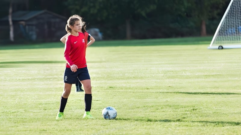 Eine junge Fußballspielerin der Marymount International School steht auf dem Spielfeld mit dem Ball am Fuß vor einem Tor.