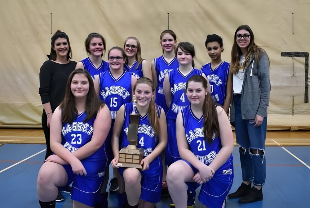 Eine Gruppe von Schülerinnen der Massey-Vanier High School posiert gemeinsam in blauen Basketballtrikots auf dem Spielfeld.