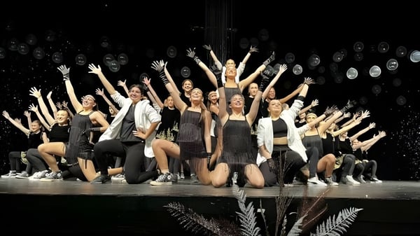 Eine Gruppe von Tänzern der Massey-Vanier High School führt eine Performance auf einer Bühne mit Spotlights auf.