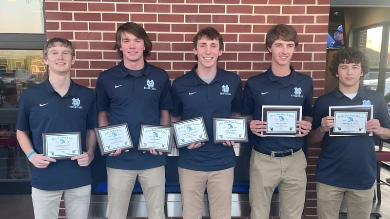 Fünf Schüler der Mater Dei Catholic High School stehen vor einer Backsteinmauer und halten Auszeichnungen und Urkunden.