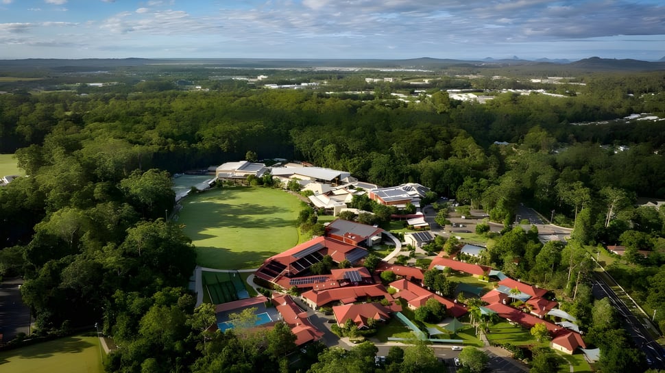 Die grüne Landschaft mit dem Matthew Flinders Anglican College Resort und Blick auf das ländliche Gebiet mit Hügeln im Hintergrund.
