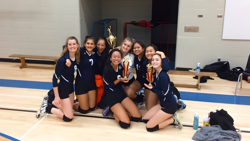 Schülerinnen der Matthew McNair Secondary School feiern ihren Sieg in der Sporthalle mit Pokalen in der Hand.