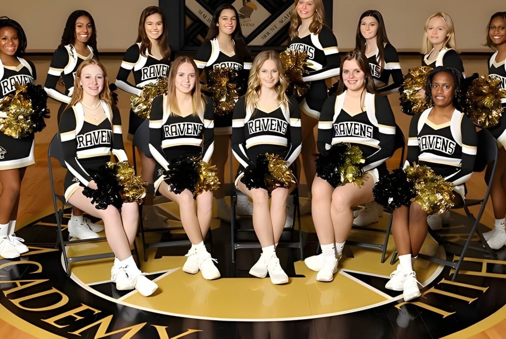 Eine Gruppe von Cheerleadern der Maur Hill-Mount Academy posiert gemeinsam auf dem Basketballfeld.