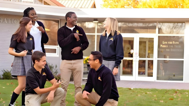 Schüler der Maur Hill-Mount Academy stehen vor einem Gebäude mit dem Schild Graduation und unterhalten sich auf einer Grünfläche.