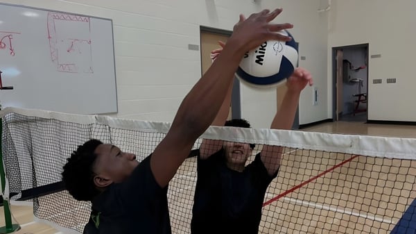 Eine Person in schwarzem Shirt spielt Volleyball auf dem Sportplatz der École secondaire publique Maurice Lapointe.