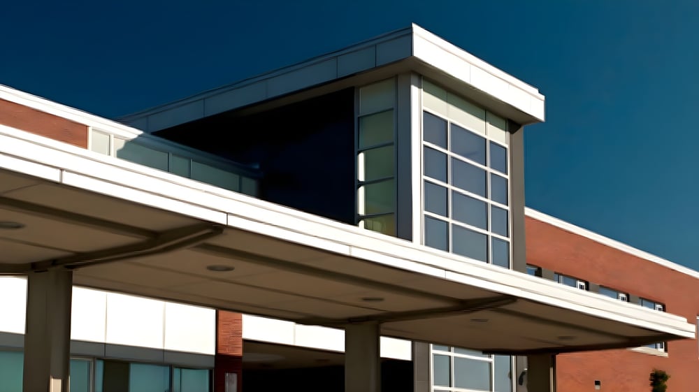 Das moderne mehrstöckige Gebäude der Maxwell Heights Secondary School mit Glas- und Backsteinfassade unter klarem blauem Himmel.