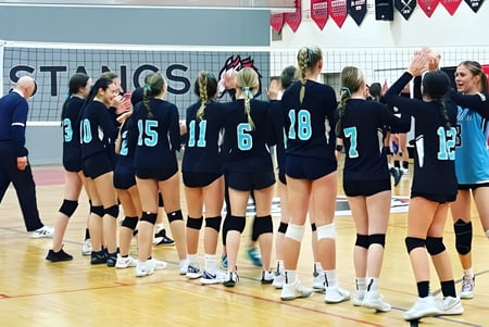 Eine Gruppe weiblicher Volleyballspielerinnen steht auf dem Spielfeld der Maxwell Heights Secondary School.