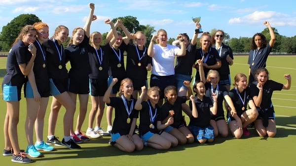 Eine Gruppe junger Sportlerinnen feiert gemeinsam auf dem Sportplatz der Mayfield School.
