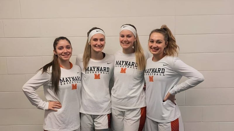 Vier Schülerinnen der Maynard High School stehen im Basketball-Trikot zusammen in der Umkleidekabine.