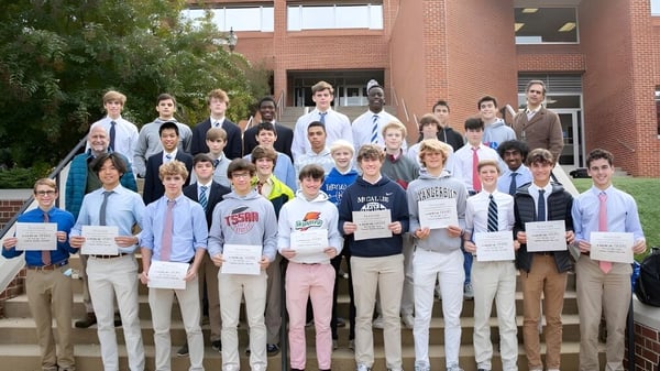 Eine Gruppe Schülerinnen und Schüler der McCallie School steht vor einem Backsteingebäude und hält Schilder sowie Urkunden.