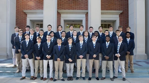 Eine Gruppe Schüler der McCallie School steht vor einem ziegelroten Gebäude mit Säulen und bogenförmigen Fenstern.