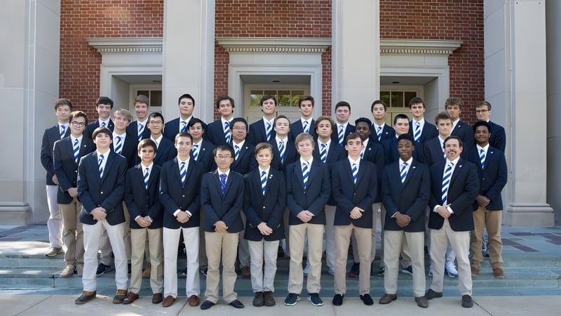 Eine Gruppe Schüler der McCallie School steht vor einem ziegelroten Gebäude mit Säulen und bogenförmigen Fenstern.