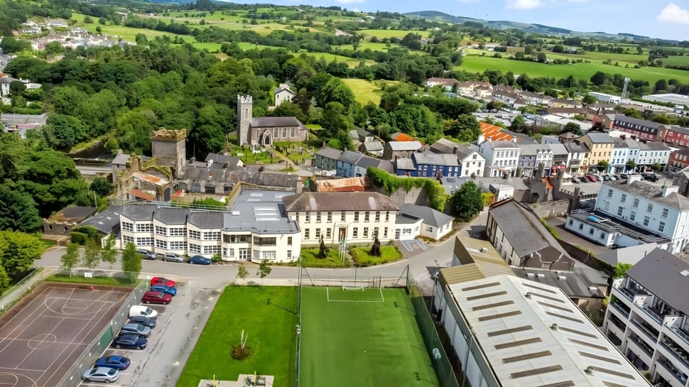 Blick auf den Campus des McEgan College mit einem Sportfeld und Gebäuden in einem grünen Tal.