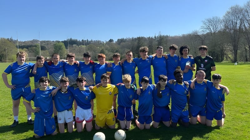 Eine Gruppe junger Fußballspieler der McEgan College steht auf einem Rasenfeld mit Bäumen im Hintergrund.