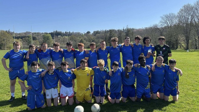 Eine Gruppe junger Fußballspieler in blauen und gelben Trikots posiert auf einem Spielfeld auf dem Campus des McEgan College.
