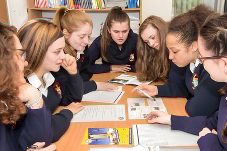 Eine Gruppe von Schülerinnen und Schülern des McEgan College arbeitet gemeinsam an einem Tisch im Klassenraum.