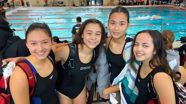 Eine Gruppe Schülerinnen der École Secondaire R.A. McMath Secondary School posiert vor dem Schwimmbecken.