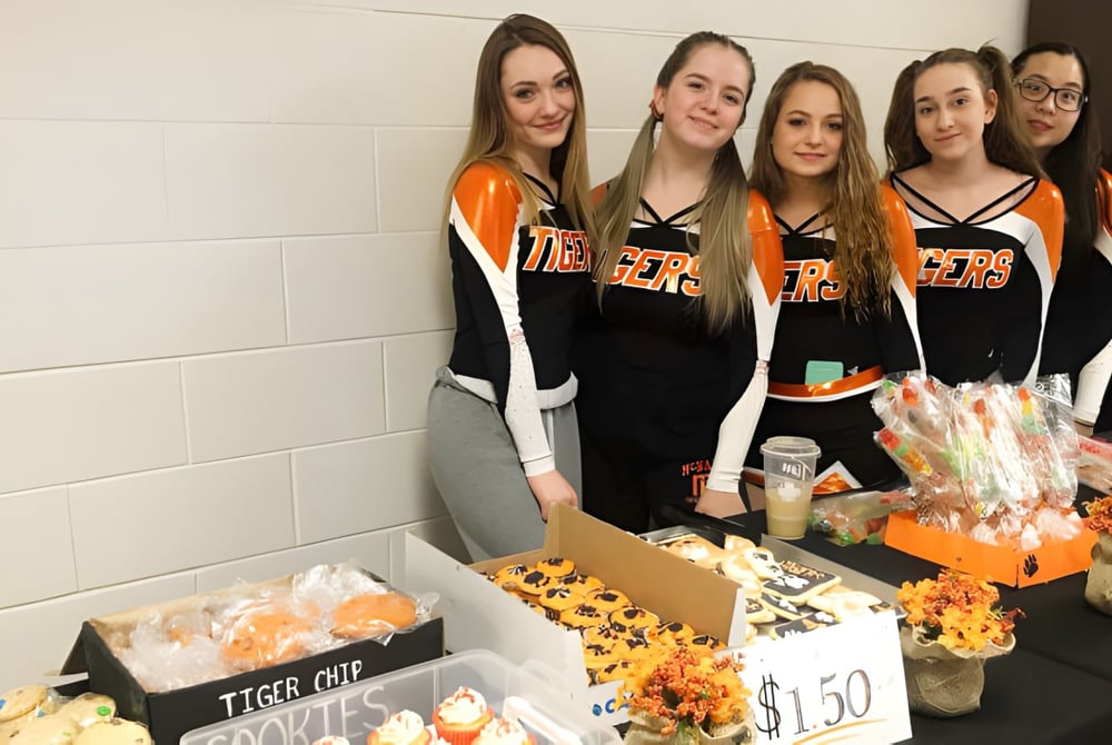 Eine Gruppe von Schülerinnen der McNally High School steht gemeinsam vor einer Wand und verkauft unterschiedliche Gegenstände.