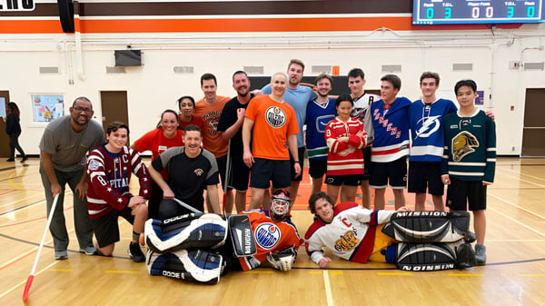 Eine Gruppe von Schülerinnen und Schülern der McNally High School posiert als Hockeyteam in der Sporthalle.