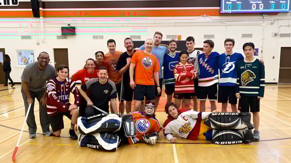 Eine Gruppe von Schülerinnen und Schülern der McNally High School posiert als Hockeyteam in der Sporthalle.