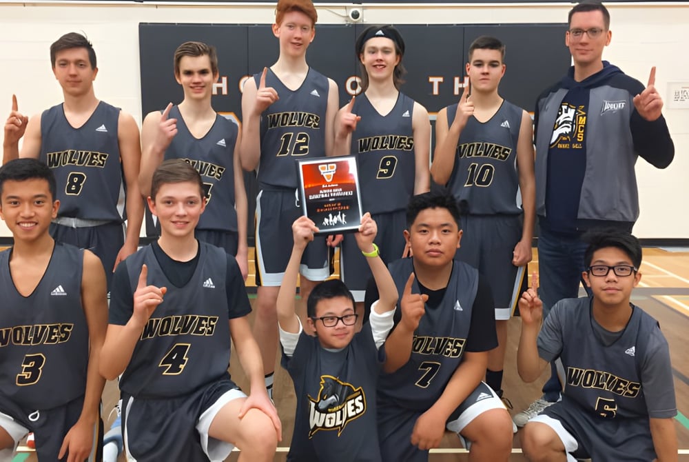 Eine Gruppe von Schülerinnen und Schülern der M.E. LaZerte Composite High School posiert gemeinsam in ihren Basketballtrikots in einer Sporthalle.