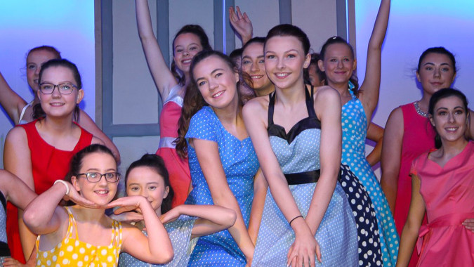 Eine Gruppe lächelnder Frauen posiert vor einer Glaswand mit Aussicht auf dem Campus der Meán-Scoil Mhuire Gan Smál.