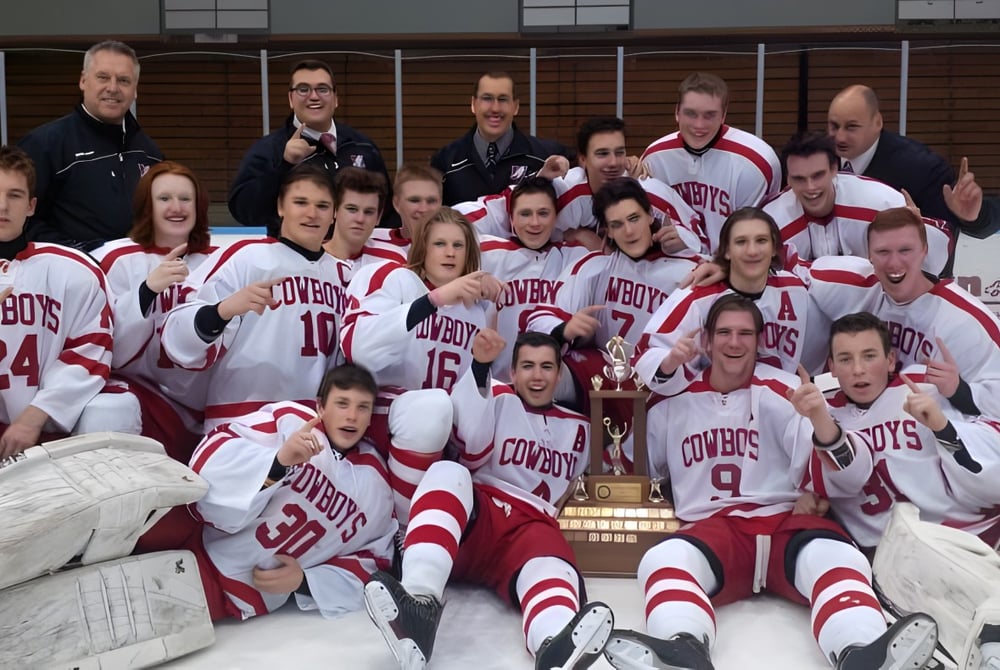 Die Hockeymannschaft der Medway High School posiert mit einem Pokal in einer Sporthalle.