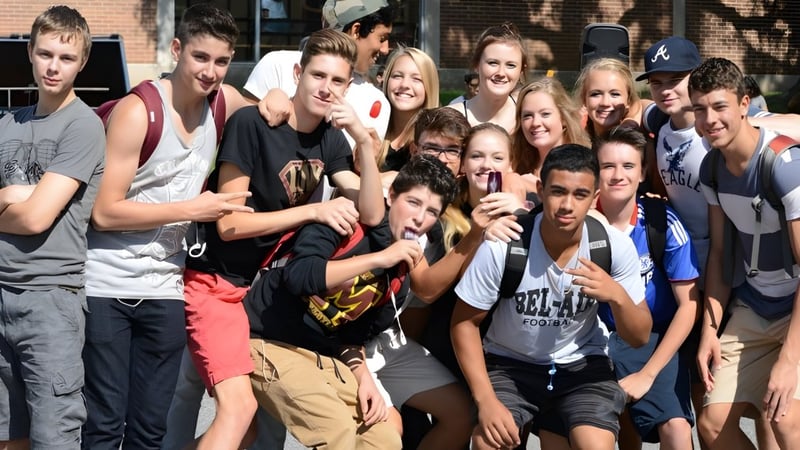 Eine Gruppe von Schülerinnen und Schülern der Medway High School posiert gemeinsam lächelnd vor einem Backsteingebäude im Freien.