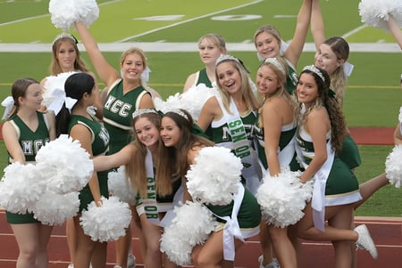 Eine Gruppe Cheerleader der Melbourne Central Catholic High School posiert zusammen auf dem Sportfeld mit erhobenen Pompons.