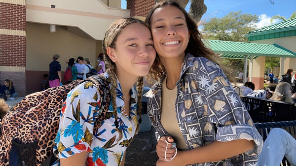 Zwei Schülerinnen stehen lächelnd vor einem Backsteingebäude auf dem Campus der Melbourne Central Catholic High School.