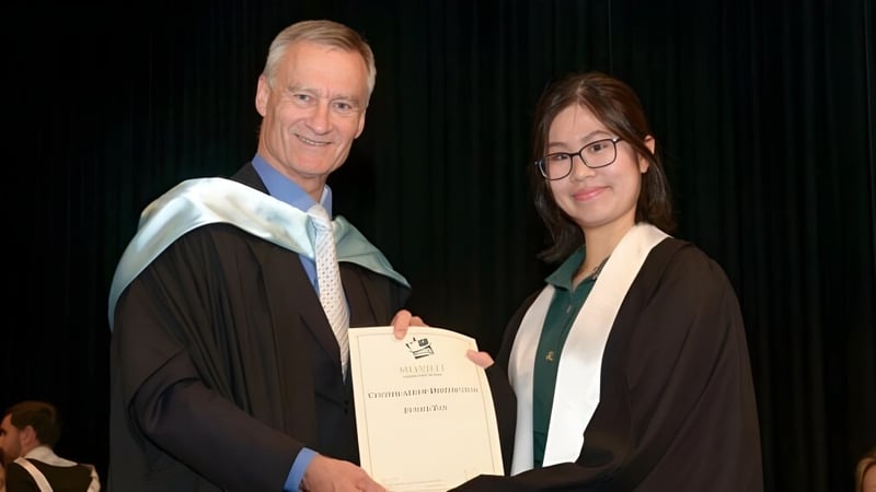 Zwei Personen tragen Roben während einer Abschlusszeremonie an der Melville Senior High School auf der Bühne.