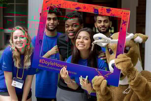 Eine Gruppe lachender Schülerinnen und Schüler posiert vor einem farbenfrohen Rahmen mit dem Text #DayleHouse auf dem Campus der Memorial University.