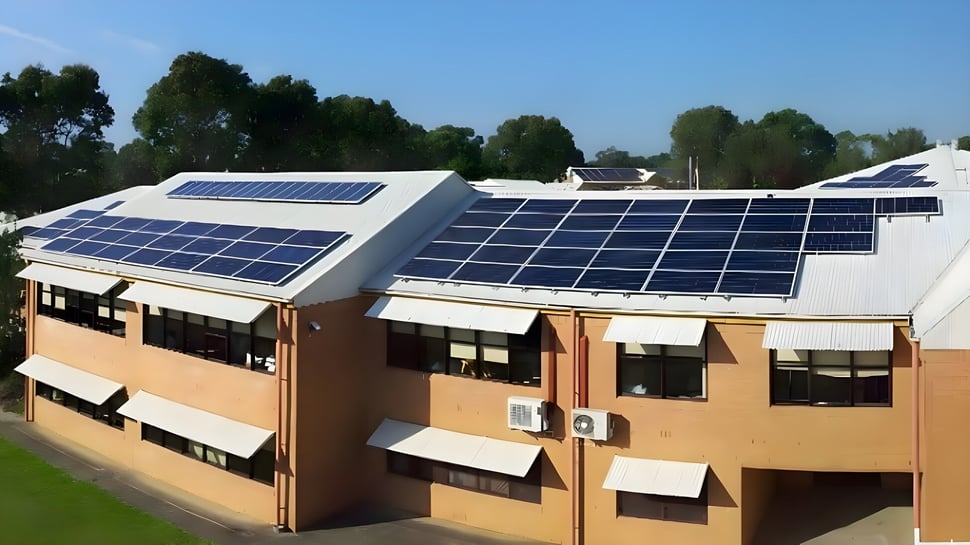 Das mehrstöckige Gebäude der Menai High School mit Solaranlagen auf dem Dach umgeben von Bäumen und einer Rasenfläche im Vordergrund.