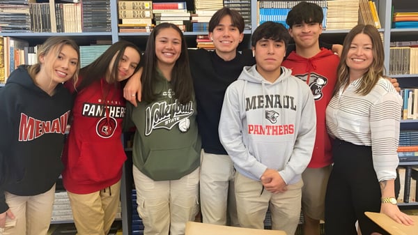 Eine Gruppe Schüler der Menaul School posiert gemeinsam vor Bücherregalen in einer Schulbibliothek.