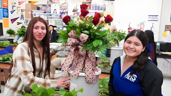 Zwei Schülerinnen des Merced Union High School District stehen in einem Blumenladen zwischen bunten Blumensträußen und Grünpflanzen.